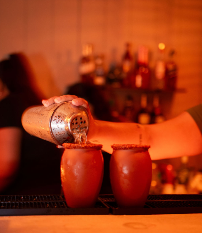 Cocktail shaker pouring into chilled clay cups
